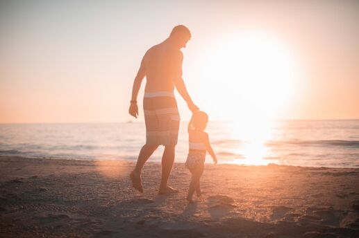 father and child on beach at sunset
