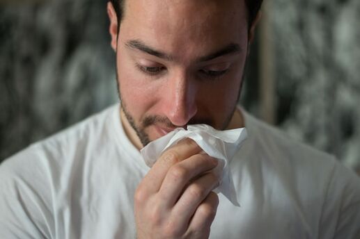 man using tissue on nose
